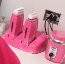 Aquecedores de cera roll-on e aquecedor de cera, em rosa, sobre a bancada do espaço